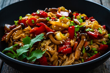 Asian style stir fried vegetables and noodles on wooden table

