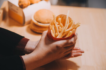 Asian woman holding french fries and eating happily in restaurant