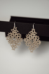 closeup hands of tatted earrings jewelry. hobby, creative accessories concept.