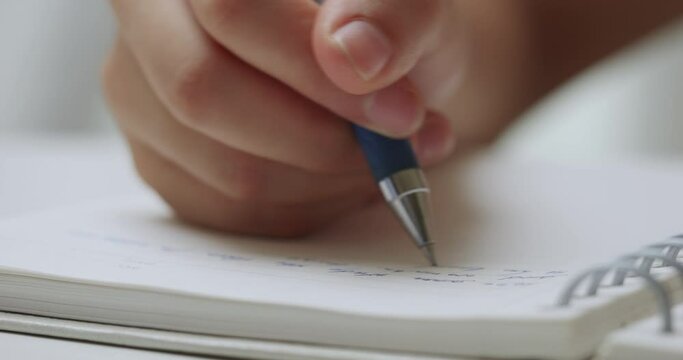 Close up of a woman's hand writing with a pen. 
