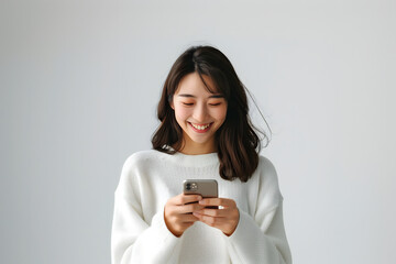 Fototapeta premium Smiling young asian woman using mobile phone on white background.