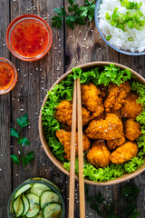 Takeaway food - fried breaded chicken nuggets and vegetables on wooden table
