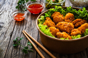 Takeaway food - fried breaded chicken nuggets and vegetables on wooden table
