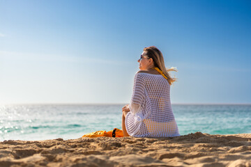 Beautiful woman sitting and sunbathing on sunny beach
