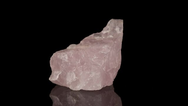 Polished mineral stone rose quartz rotates in a circle on a black background