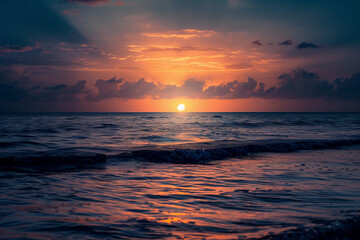 Obraz premium The sun is setting over the ocean, casting a warm glow on the water