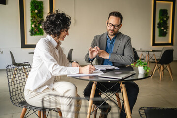 Mature woman sign insurance or contract to adult man in cafe