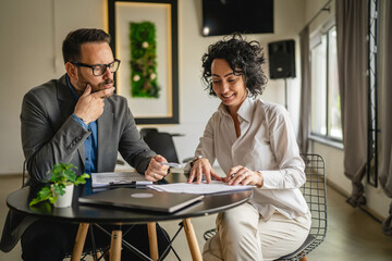 Mature woman sign insurance or contract to adult man in cafe