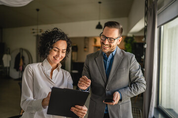 Colleagues stand in cafe woman hold document and man hold mobile phone
