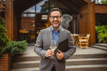 Portrait of adult man stand in front of winery hold wine and clipboard