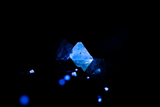 Scheelite under Short wave ultraviolet. Specimen From Yaogangxian mine, Chenzhou, Hunan, China. photography isolated on black background. macro detail close-up rough raw unpolished