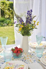 A bouquet of wildflowers and strawberries on the table for the Midsommar holiday.