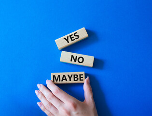 Yes No Maybe symbol. Concept word Yes No Maybe on wooden blocks. Beautiful blue background. Businessman hand. Business and Yes No Maybe concept. Copy space.