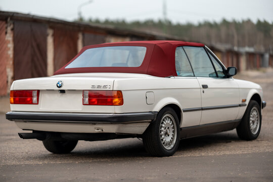 Riga, Latvia - April 1, 2024: Back view of the white classic BMW E30 car with red roof.