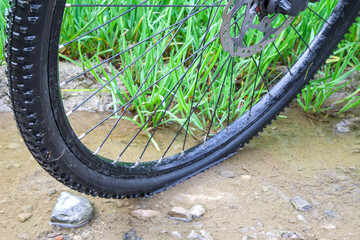 The sturdy tread of a trekking bike tire is showcased in a puddle off the beaten path on a rugged...
