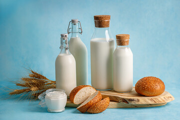 Dairy products, bread, milk bottles on light blue background. Jewish holiday Shavuot concept