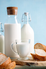 Dairy products, bread, milk bottles on light blue background. Jewish holiday Shavuot concept