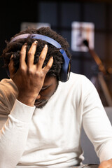 Gamer wearing headphones face palming himself in frustration after getting game over message while playing videogame. Man feeling depressed while playing on gaming console after losing
