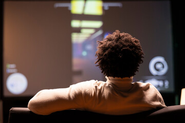 Man seeing livestream footage on smart TV from professional streamer playing videogame. BIPOC gamer...