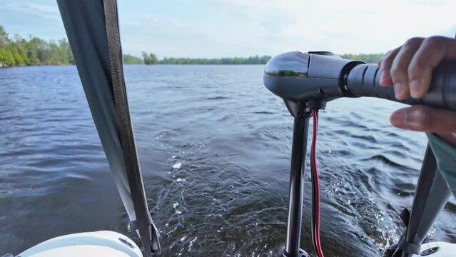 Close up of trolling electric motor at inflatable boat while boating at the lake. Leisure activity of travelling by boat and recreational use of boat vessel. Sports activities fishing and exploring.