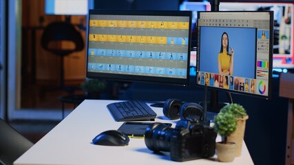 Creative agency studio desk with photo processing software interface on computer screens, graphic tablet and professional camera, panning shot. Image editing program displayed on PC monitors, close up