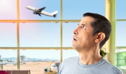 Portrait man with a fear to fly and looking with panic at a plane that is flying with copy space