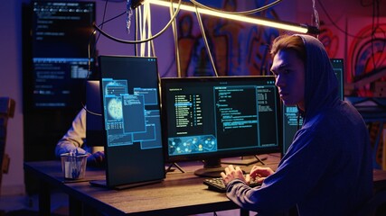 Fototapeta premium Skilled hacker group members deploying malware on unaware victims computers, stealing sensitive and private information, selling it on darknet crime haven to highest bidder