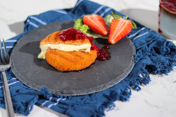 Fresh made fried camembert cheese with cranberry sauce on top, grey stone plate