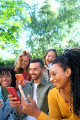 Vertical. Group of smiling young friends using smart mobile phones app together. Millennials addicted to technology trends. University students and Social media online community. Focus on Latina woman