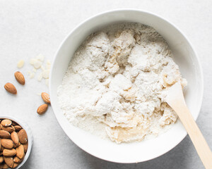 making almond biscotti dough in a white bowl, process of making almond cantucci cookie dough in ceramic mixing bowl