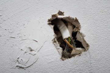 Damaged Wall With Exposed Electrical Wires Inside a Residential Home During Daytime