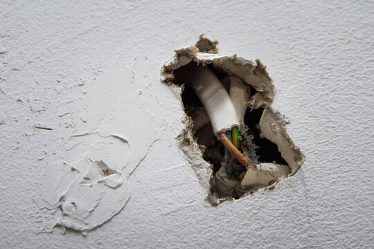 Damaged Wall With Exposed Electrical Wires Inside a Residential Home During Daytime