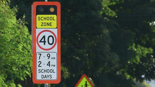Medium shot red flashing School zone 40 km/h speed limit sign QLD Australia trees copy space