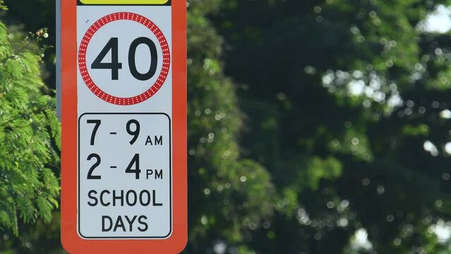 Close-up shot red flashing School zone 40 km/h speed limit sign QLD Australia trees copy space