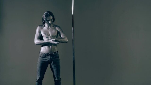 Flexible man exercises on pylon. Sexy flexible man demonstrates sexy flexible body. Flexibility stretching. Flexible female body. Pole dance. Male stripper. Strip dance, man pole dancing.