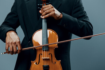 Closeup portrait of a man in a suit holding a violin on a gray background, showcasing elegance and...