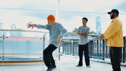 Hipster perform break dance while friend encourage him at mall. Diverse or multicultural street...