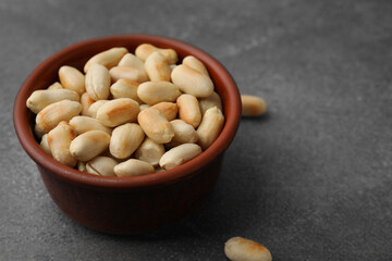 Roasted peanuts in bowl on brown table, closeup. Space for text