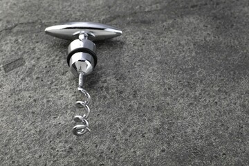 One metal corkscrew on grey textured table. Space for text