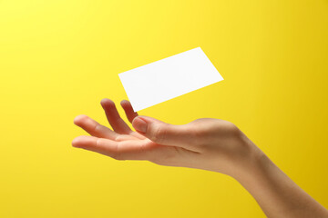 Woman with blank business card on yellow background, closeup. Mockup for design