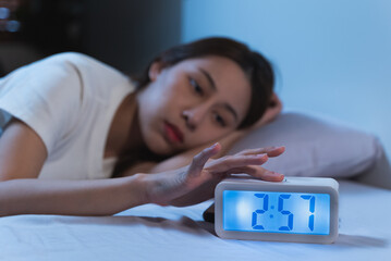 Close up on alarm clock in the night and woman have insomnia on the bed