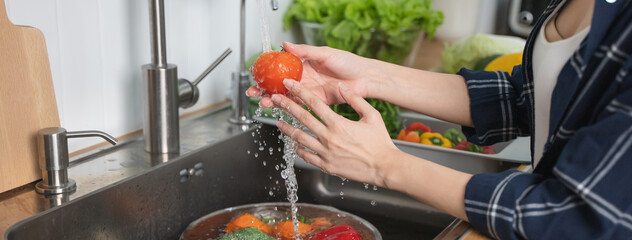Close up of hands people washing vegetables by tap water at the sink in the kitchen to clean...
