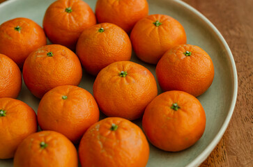 Clementine oranges in plate naturally lit arranged wooden background