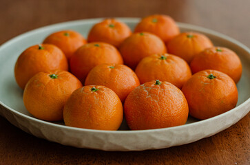 Clementine oranges in plate naturally lit arranged wooden background