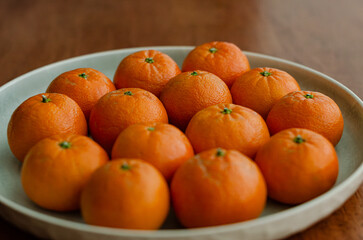 Clementine oranges in plate naturally lit arranged wooden background