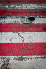 Old worn red and white pedestrian crossing across the road. Road markings, safety.