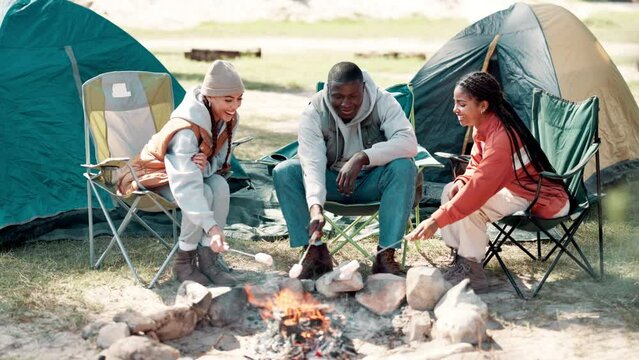 Friends, camping and group cooking with fire on adventure in forest or trekking in mountains. Flame, smoke and people with candy marshmallows at campfire in summer, countryside or relax at bonfire