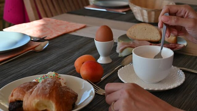 giovane donna fa colazione con un cappuccino, cornetto uova al tavolo di un bar all'aperto