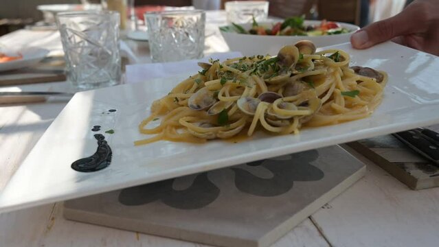 linguine ai frutti di mare serviti in un piatto sul tavolo di un ristorante all'aperto in estate