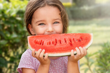 Happy girl child holding watermelon in backyard